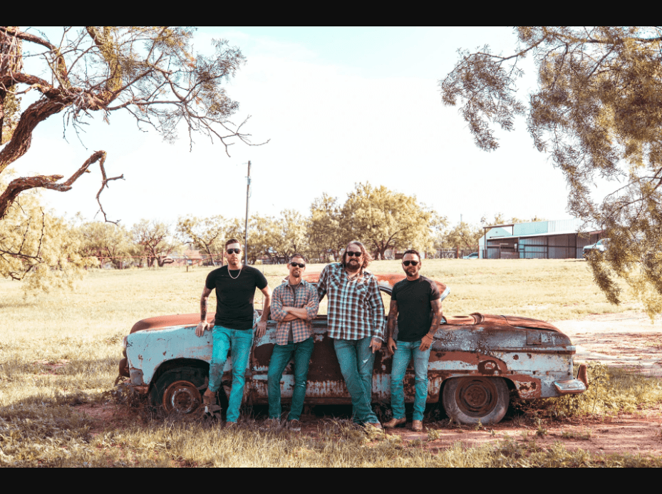 Shane Terrell & The Stumblers leaning against a vintage truck in a Texas field